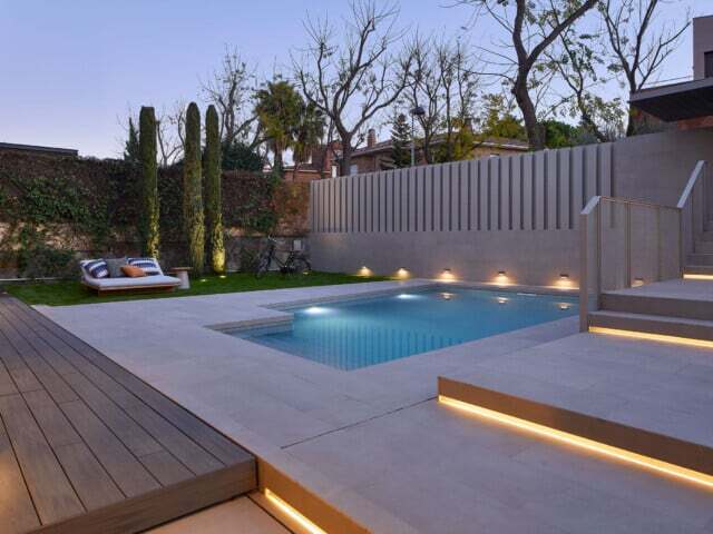 Reforma de exterior de patio de casa moderna con piscina con iluminaciones y decoración.